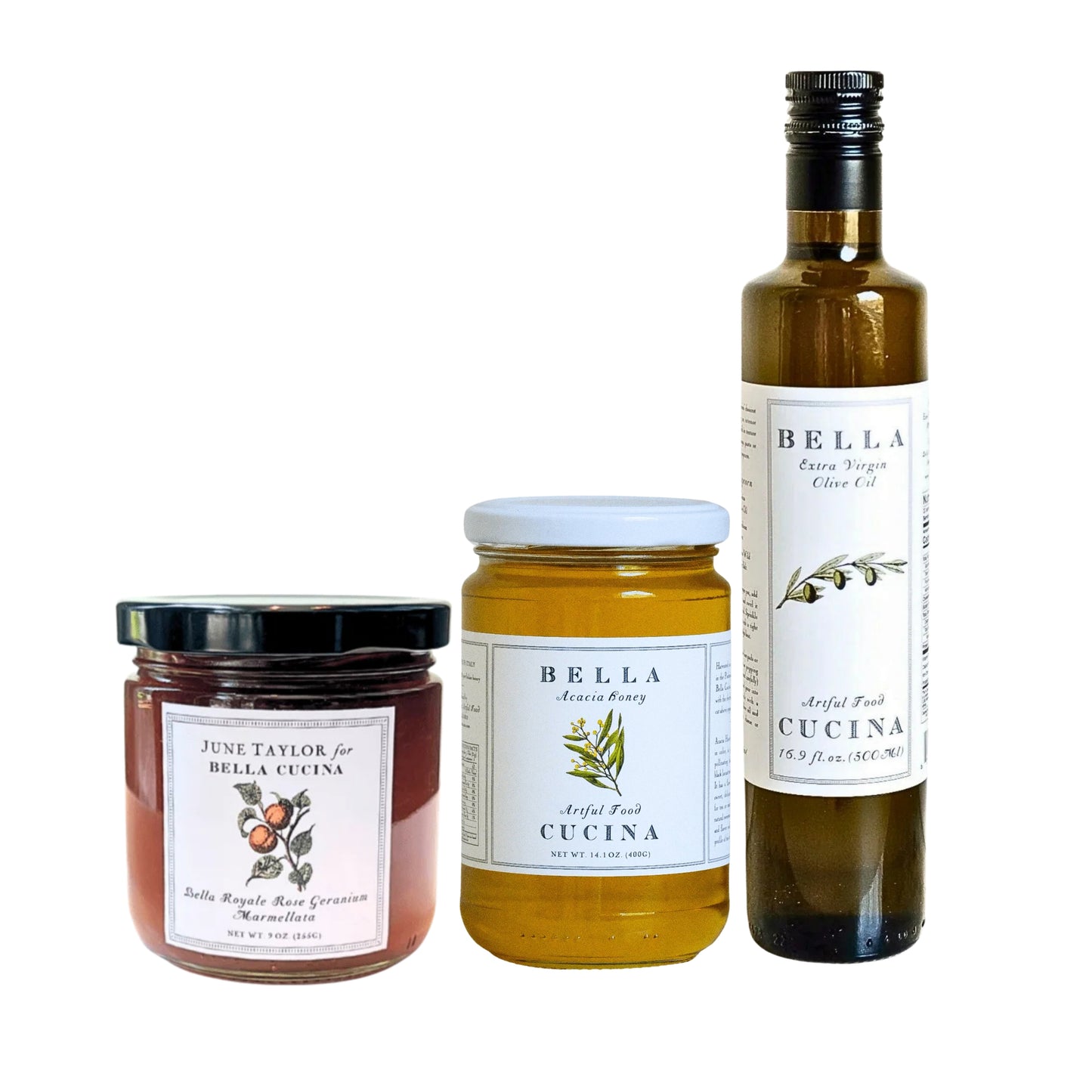 Three Bella Cucina products on a white background: a bottle of olive oil, a jar of angel food cake mix, and a jar of marzipan. The labels show the Bella Cucina brand with botanical illustrations.