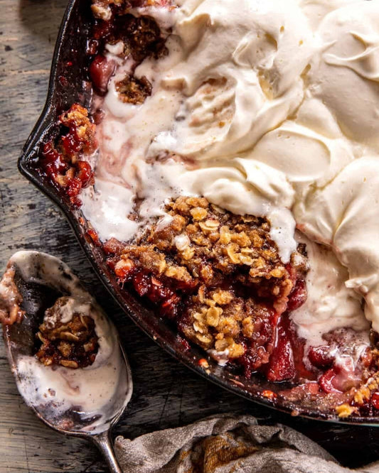Golden summer berry granola crisp in a baking dish, served warm with a dollop of whipped Preserved Lemon Cream.