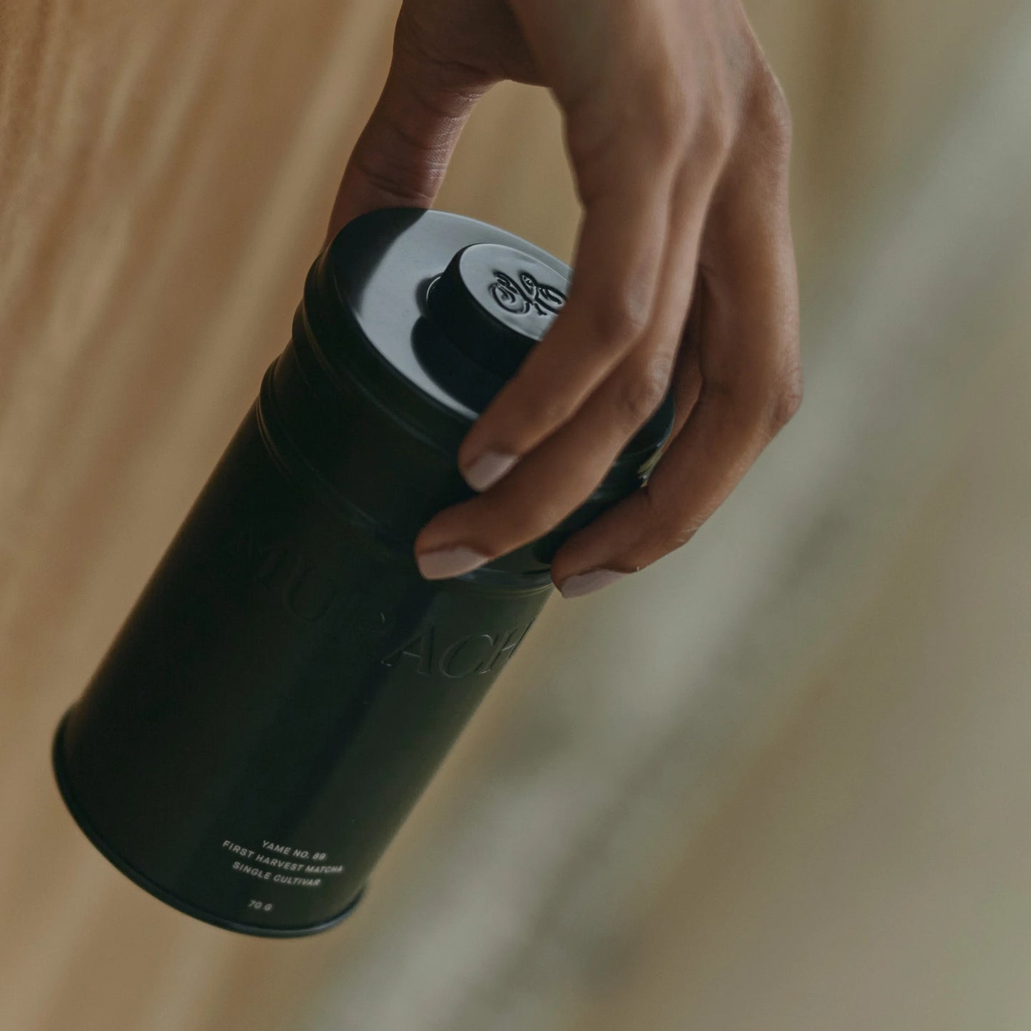 Hand holding a black travel mug with a blurred background