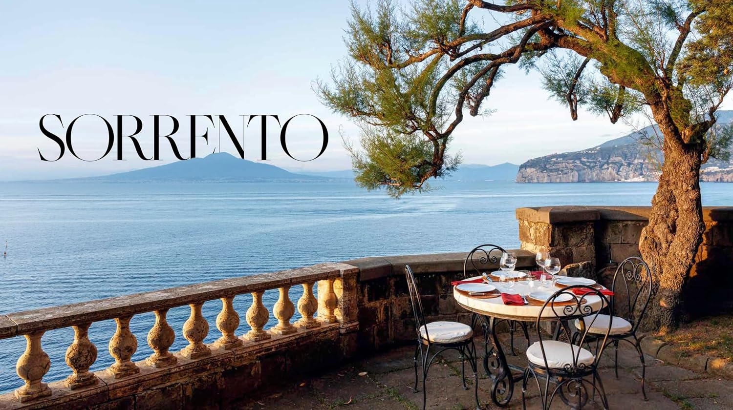 Outdoor dining table with chairs by a scenic coastal view in Sorrento, Italy.