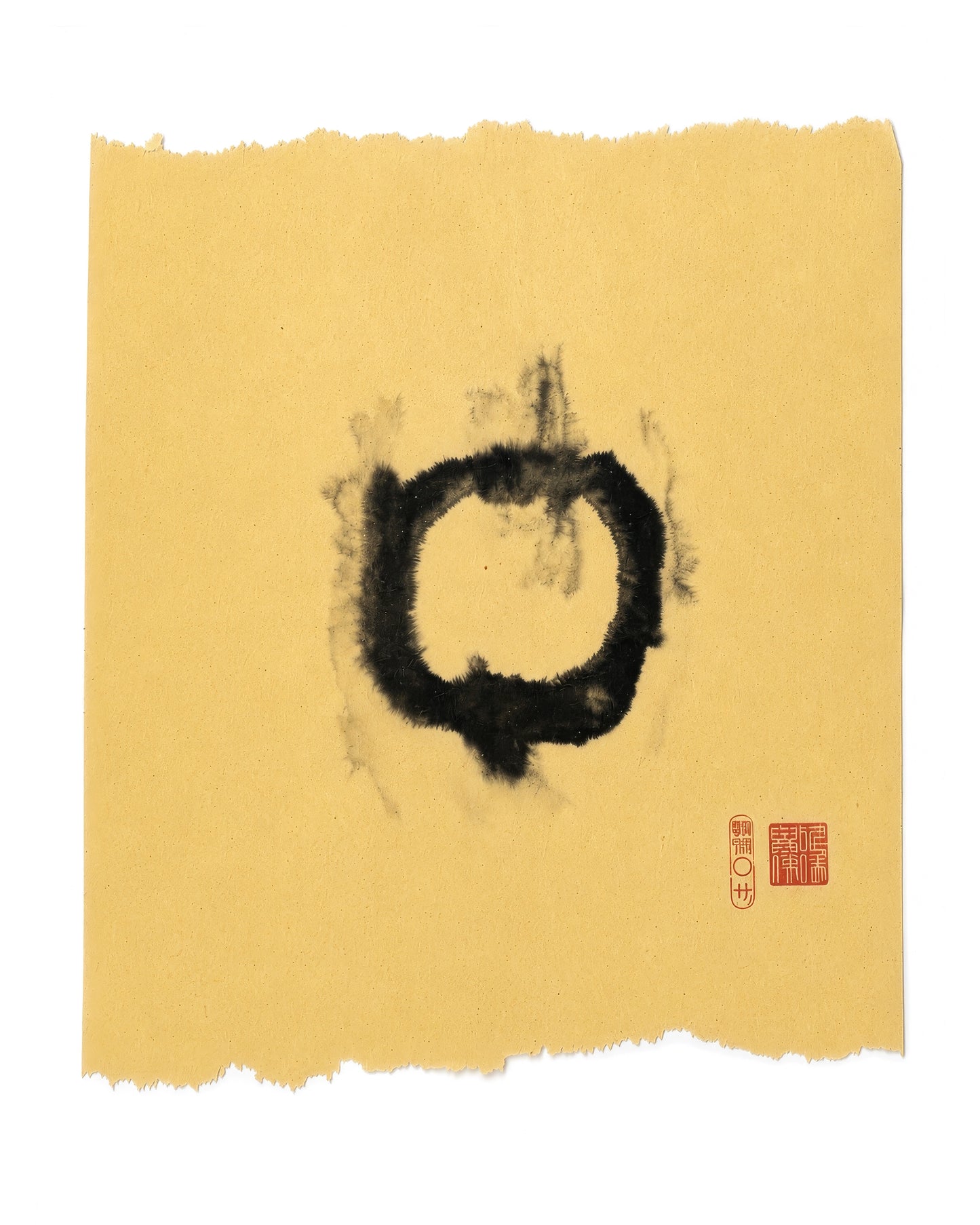 A piece of textured yellow paper with torn edges, featuring a central black ink calligraphy character and a small red artist seal in the lower right, shown against a plain white background.