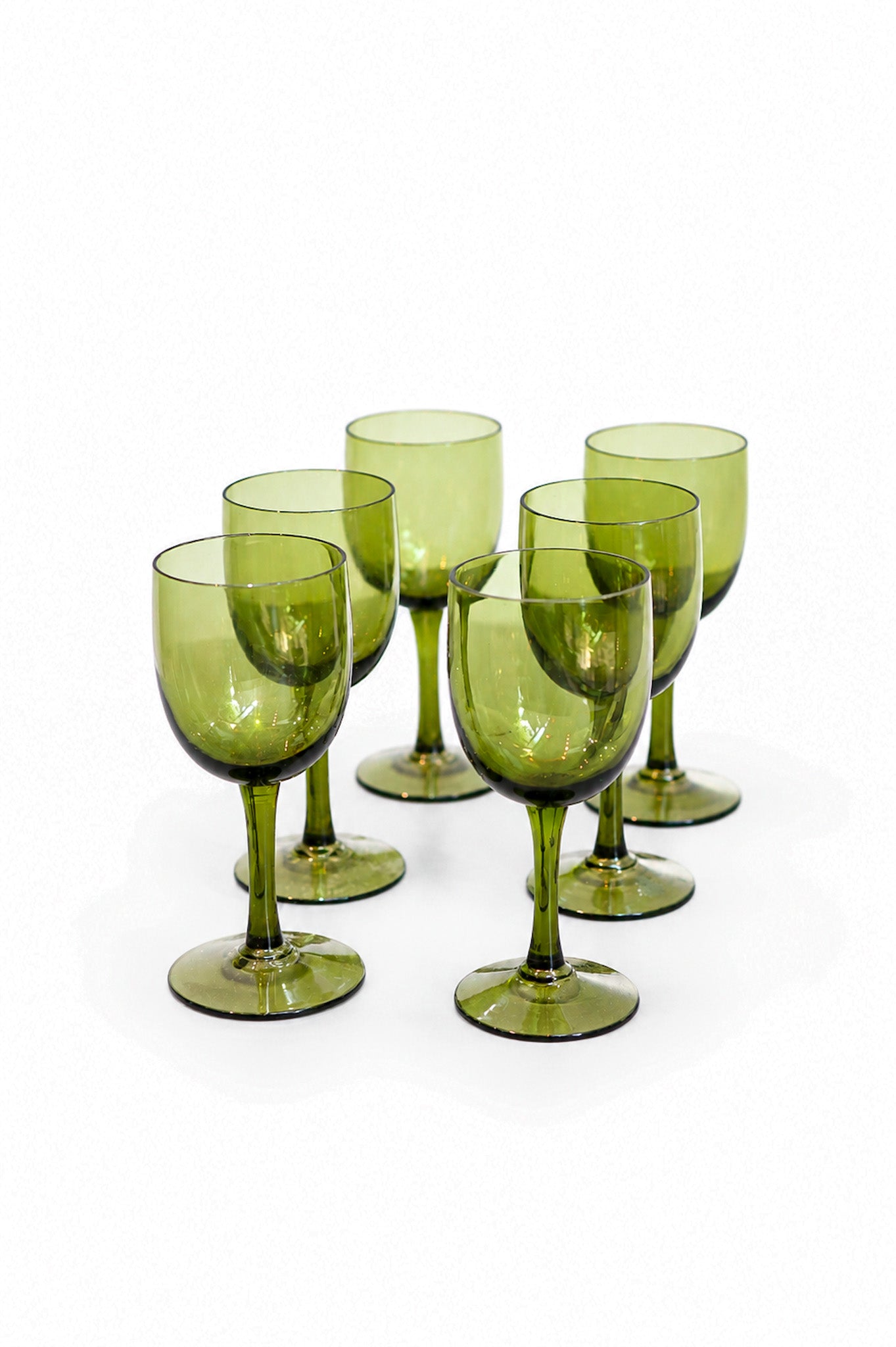 Six translucent olive green wine glasses arranged together on a clean white background. A one-of-a-kind vintage Italian set at Bella Cucina.