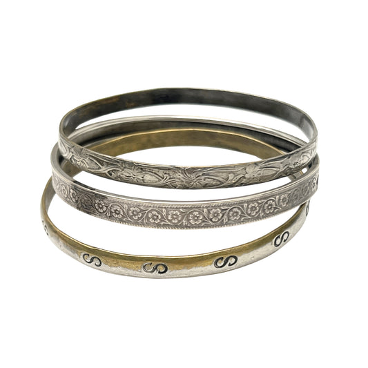 Set of four silver and gold bangles with intricate designs on a white background